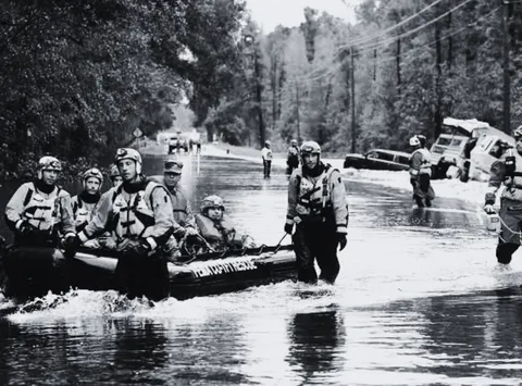 Swift-water rescue team towing a boat of evacuees down a flooded street